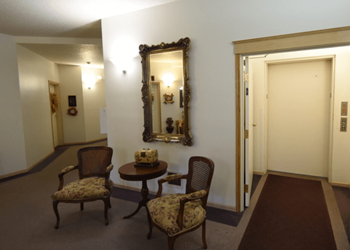 A hallway with a table and chairs and a mirror on the wall at Eighth Street Manor Apartments, Fargo